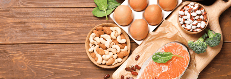 Tavolo con uova, salmone, avocado, mandorle e verdure verdi — i cibi che danno energia del Metodo Sautón Title: cibi che danno energia