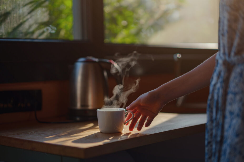 Tazza di infuso caldo accanto a finestra luminosa al mattino — abitudini quotidiane contro la stanchezza cronica