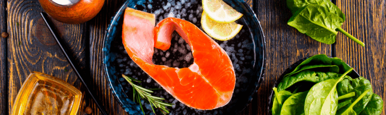 Tavola con pesce azzurro, verdure verdi e semi: alimentazione per gestire il cortisolo alto