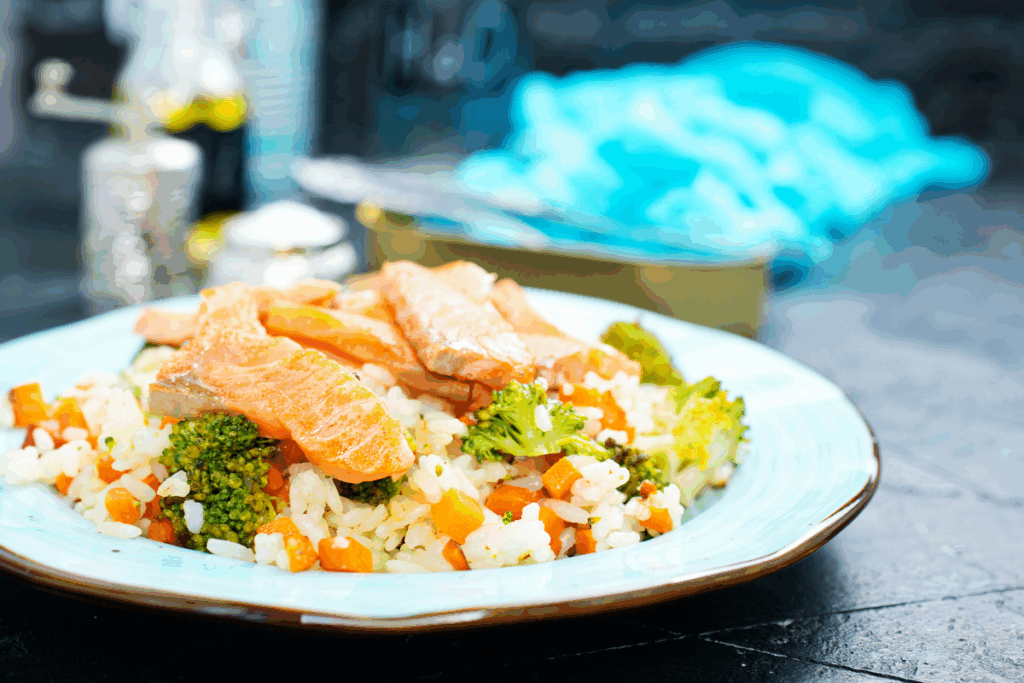 Piatto con salmone, riso integrale e verdure verdi su tavolo di legno — recupero post allenamento