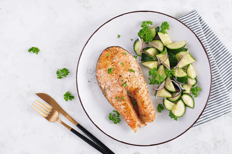 Piatto con salmone al vapore, zucchine e finocchi su tavolo di legno chiaro — reflusso gastroesofageo