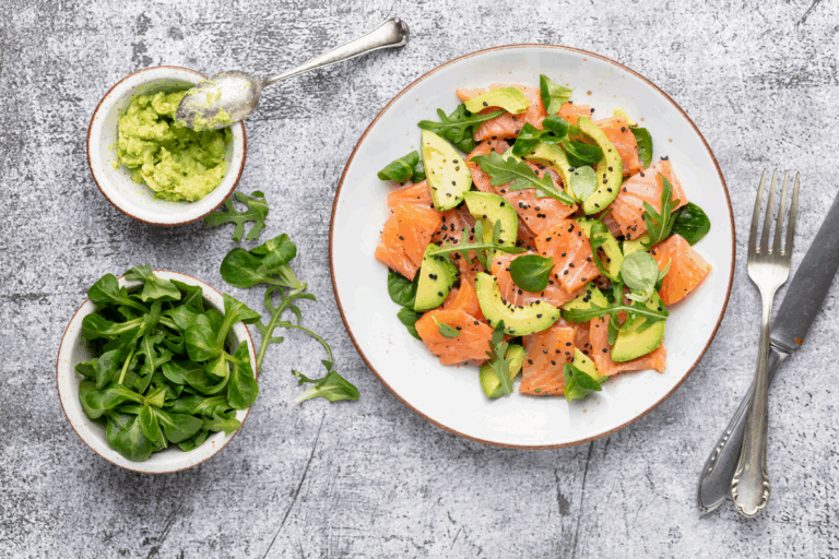 Piatto con salmone, avocado, semi e verdure verdi su tavolo di legno — switch metabolico
