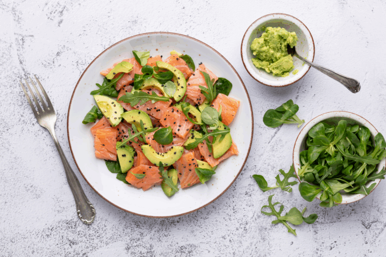 Piatto con salmone, avocado e verdure verdi su tavolo di legno — trigliceridi alti