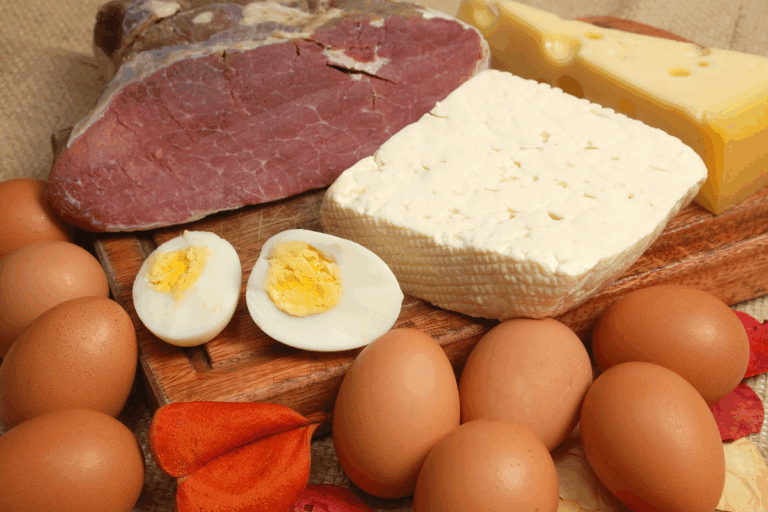 Alimenti ricchi di proteine: bresaola, grana, uova, semi di canapa e legumi su tagliere di legno